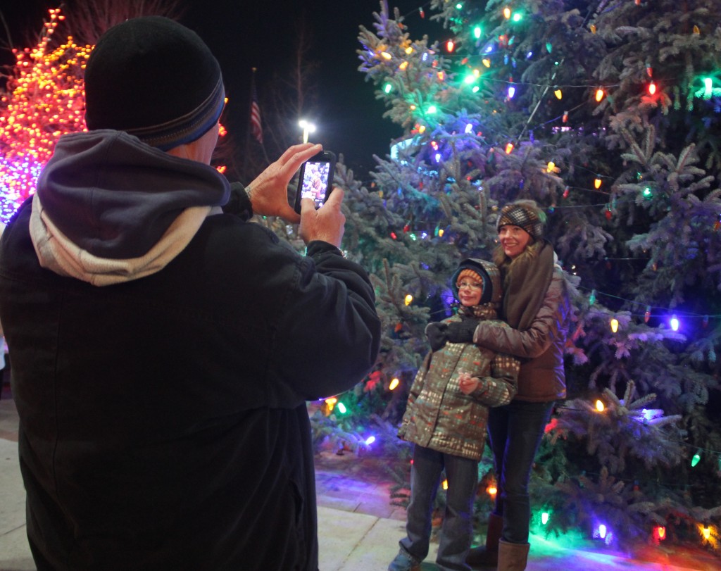 A father takes a snapshot in front of the Community Christmas Tree at one of the recent holiday events downtown.  