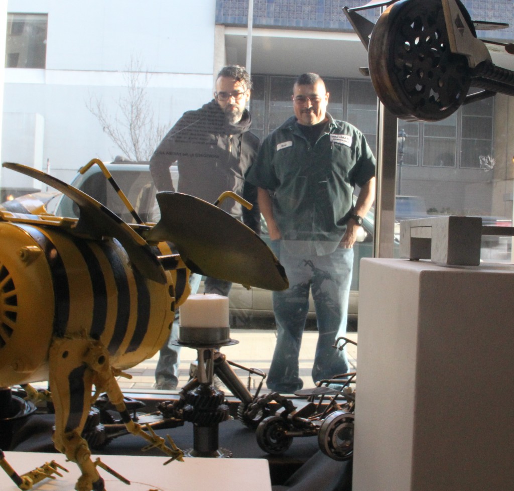 Featured Windows Alive! Artist Raul Marquez (Right) and his brother in-law James Hunter (left) admire the set up of his sculptures in one of the downtown windows designated for the popular arts project. 