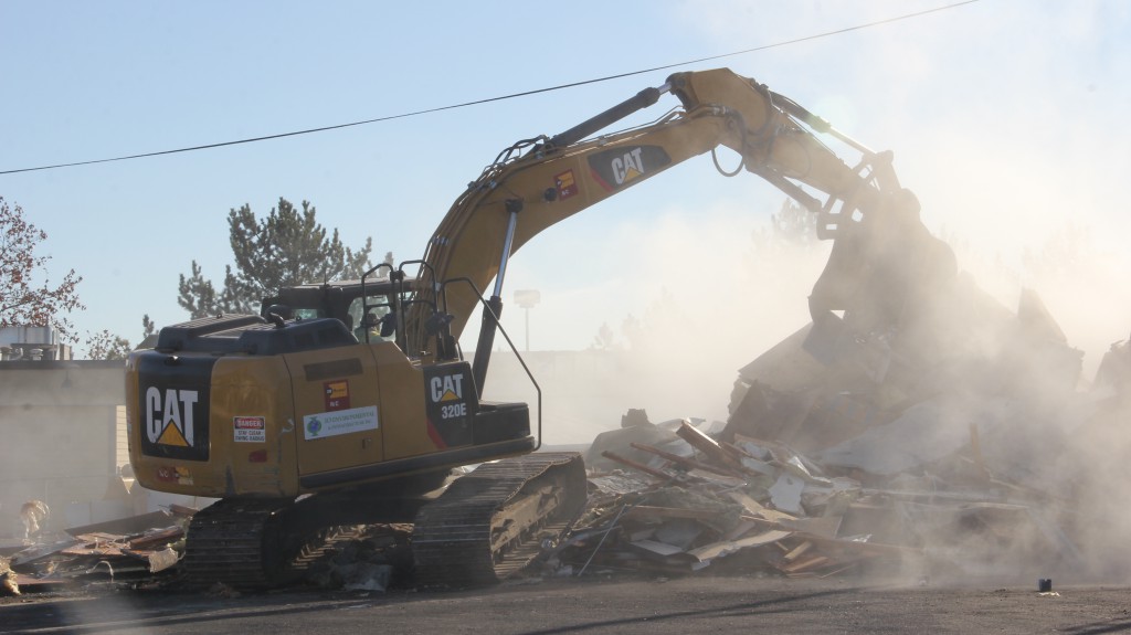 Heavy equipment creates a cloud of dust as it rips through the abandoned Tiger Mart building on 24th and Nob Hill Boulevard to begin the environmental clean up process.