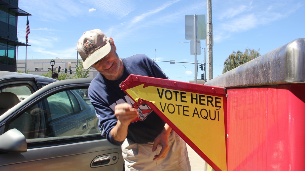 A registered voter saves a stamp and drops his primary election ballot at a collection box just down the street from Yakima City Hall.