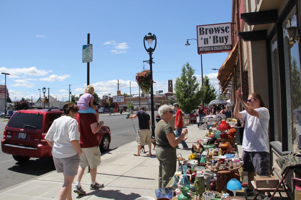 Customers peruse a vendors wares at an antiques sidewalk sale along “antique row” on Yakima Avenue.